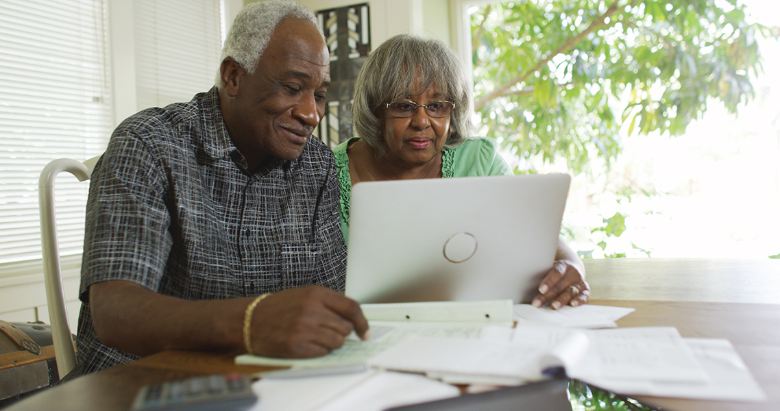 Mature African couple reading on their laptop computer