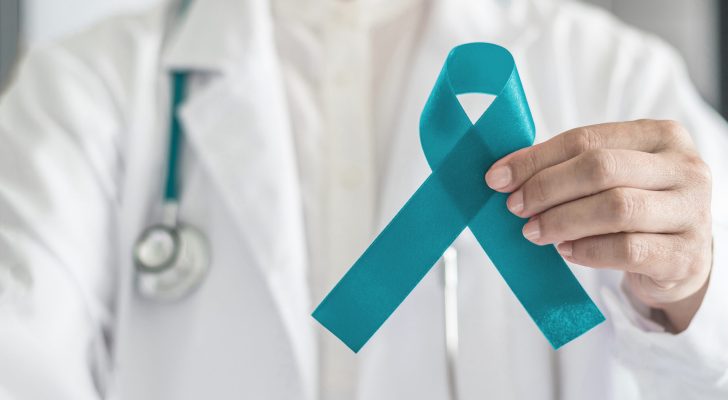 Teal awareness ribbon in doctor's hand, symbolic bow color for supporting patient with Ovarian Cancer, PCOS and PTSD Illness
